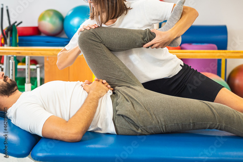 Tableau sur toile Female physiotherapist doing a treatment for the mobility of the male patient knees and hips
