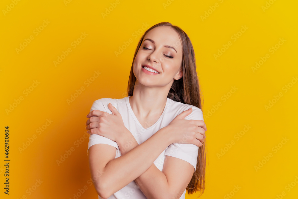 Obraz premium Close-up portrait of attractive lovely girl hugging herself comfort cozy dream isolated over bright yellow background