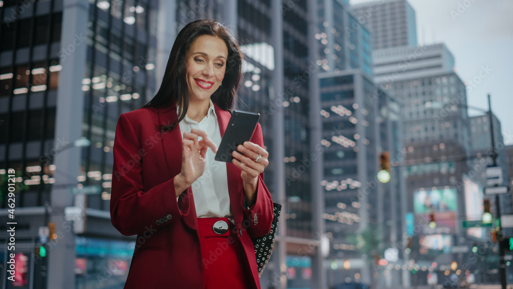 Portrait of Successful Adult Businesswoman Using Smartphone on the Street in a Big City. Confident Manager Connecting with People Online, Messaging, Browsing Internet on Her Way to Office.