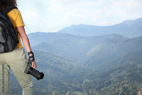 Professional photographer with modern camera in mountains, closeup. Space for text