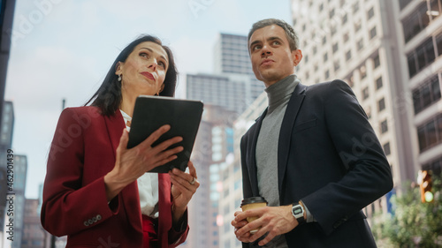 Confident Businesswoman Showing Financial Projections to Her Work Partner on Laptop Computer. Manager and Entrepreneur Discussing a Project Outside on a Street in Big City in Downtown.