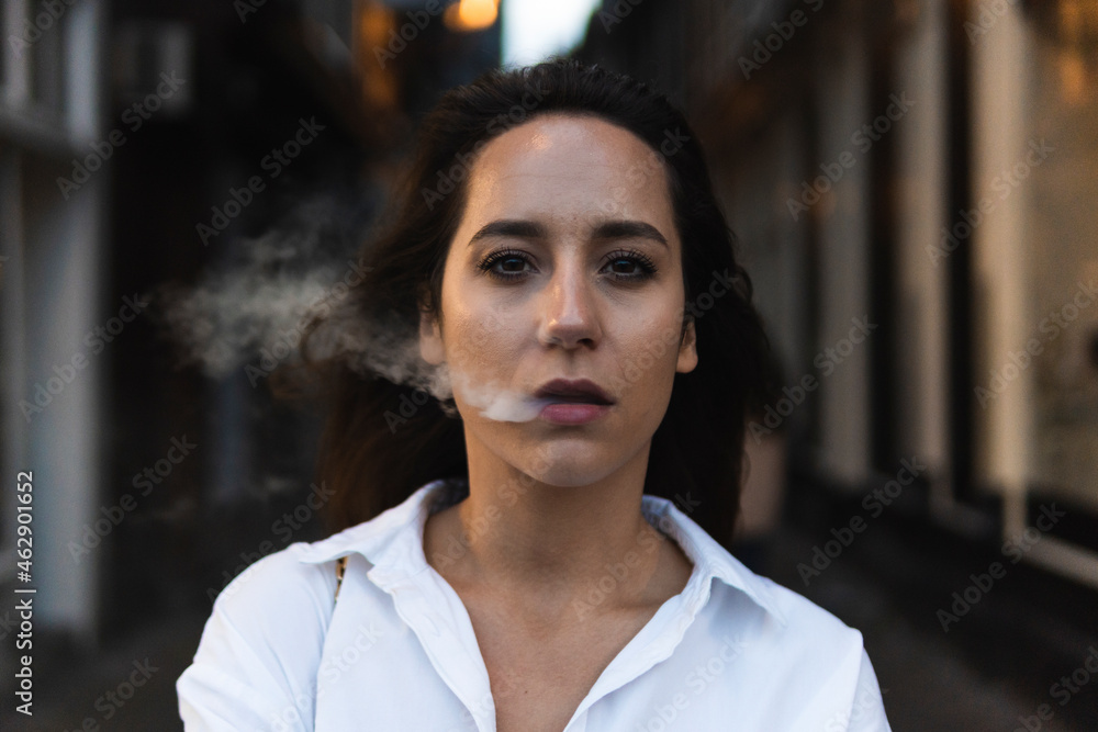 Serious woman exhaling smoke on street Serious woman exhaling smoke on street