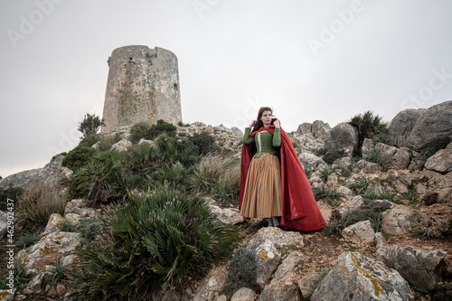 Woman in old fashioned clothes on rocky shore photo