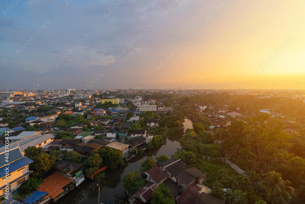 Obraz premium Aerial view of residential houses with nature trees, Wutthakat district, Bangkok City, Thailand in urban city in Asia. Residential houses, buildings at sunset.