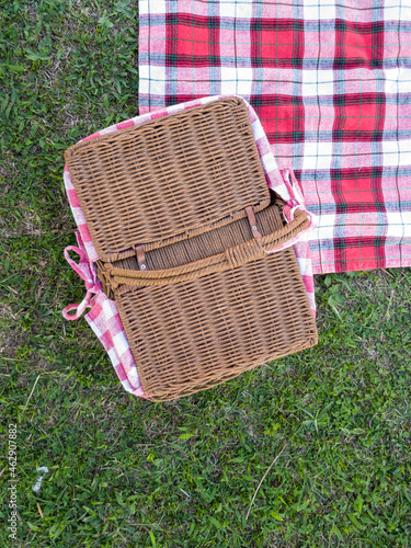 Picnic basket and plaid blanket on the lawn.