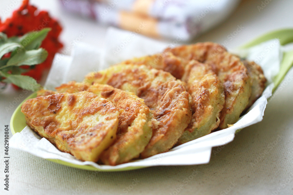 Golden slices of zucchini fried in batter. The red rowan tree symbolizes autumn.