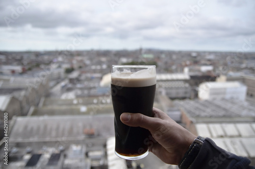 Photography dark stout pint beer in hand  at top of dublin city  isolated from background