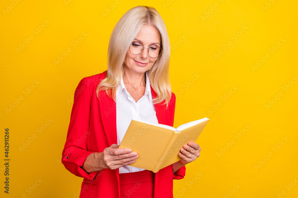 Photo of attractive mature woman read book hobby novel learning isolated over yellow color background Photo of attractive mature woman read book hobby novel learning isolated over yellow color background