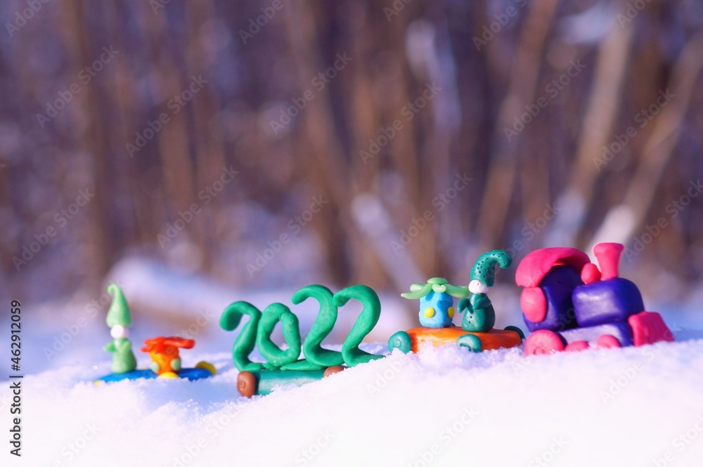 Toy train with Christmas toys and the date 2022 in the winter forest.