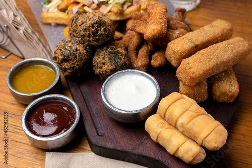 picada table with tequeños chicken sticks vegetable croquettes with assorted sauces beer and french fries