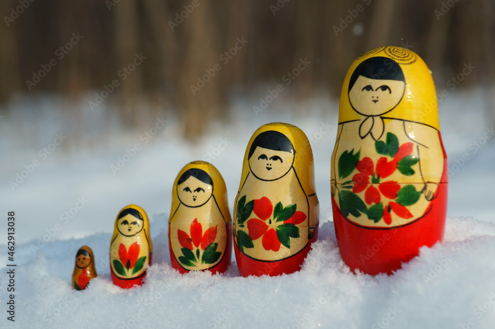 A row of nesting dolls on the background of a winter forest.