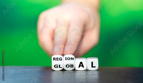 Hand turns dice and changes the word global to regional. photo