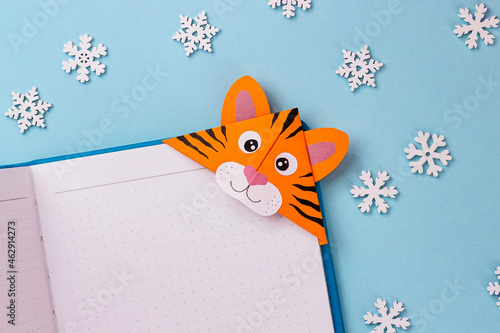 Step-by-step photo instruction on how to make a bookmark in the form of an orange tiger from paper. The symbol of the new year 2022. Step 8. Glue the eyes and draw the stripes. Done
