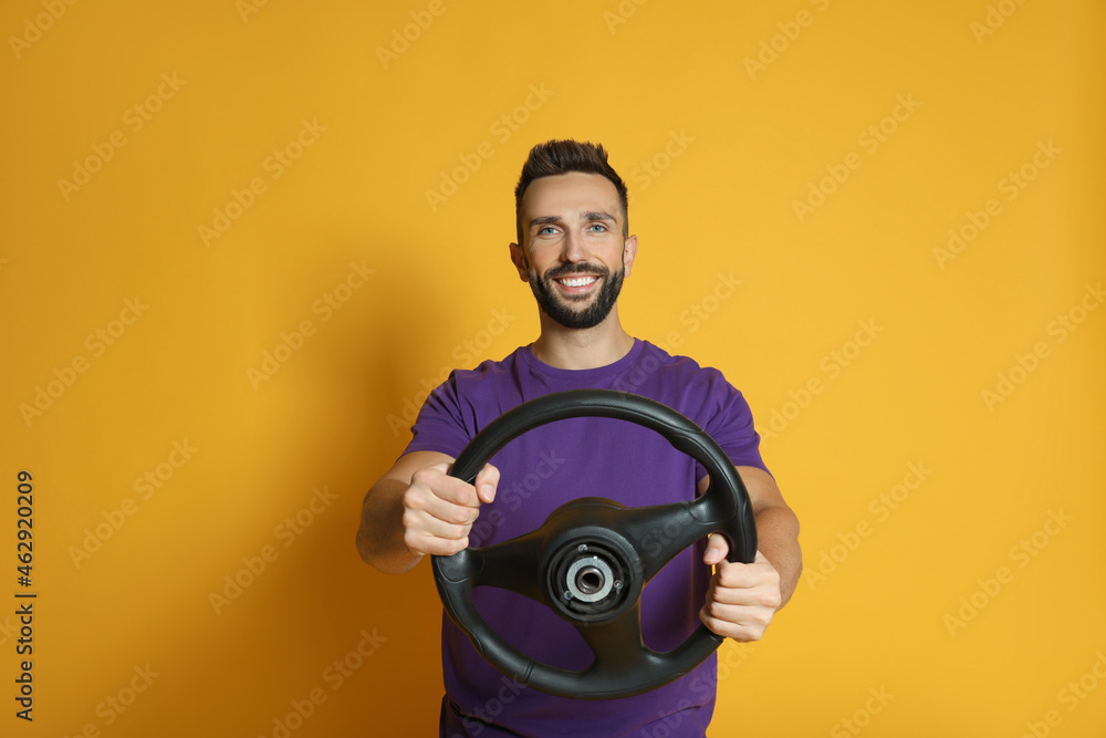 Happy man with steering wheel on yellow background Happy man with steering wheel on yellow background
