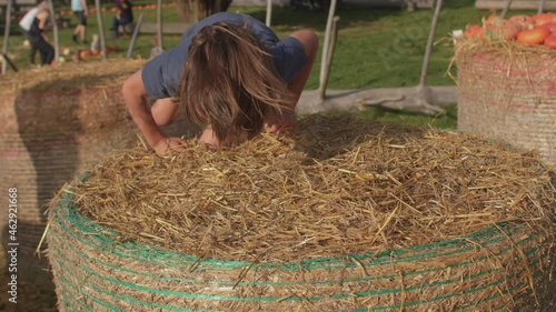 The boy jumps on the hay in the village. He leaps and falls. Dexterity and balance training. Hay underfoot. photo