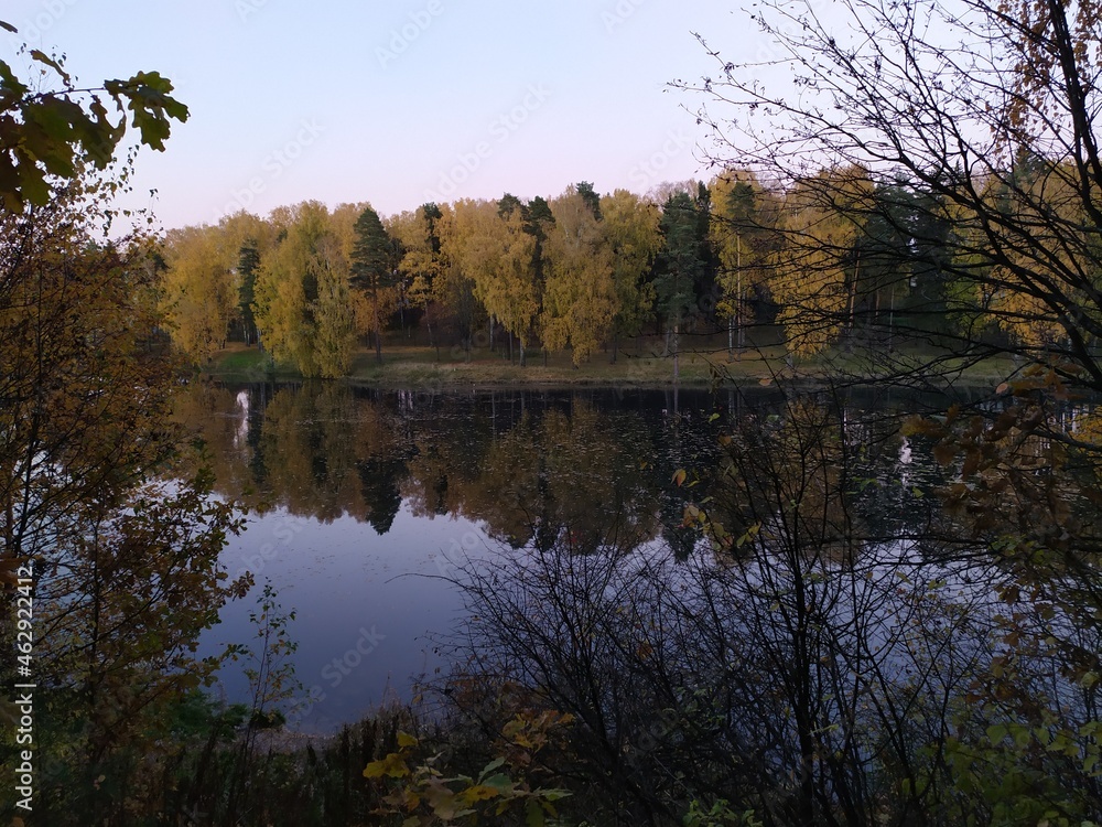 Fall landscape with reflection of trees in the calm river water in sunny autumn evening Fall landscape with reflection of trees in the calm river water in sunny autumn evening