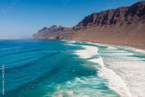 Aerial view of Famara beach with scenic mountain landscape, ocean and waves in Lanzarote island