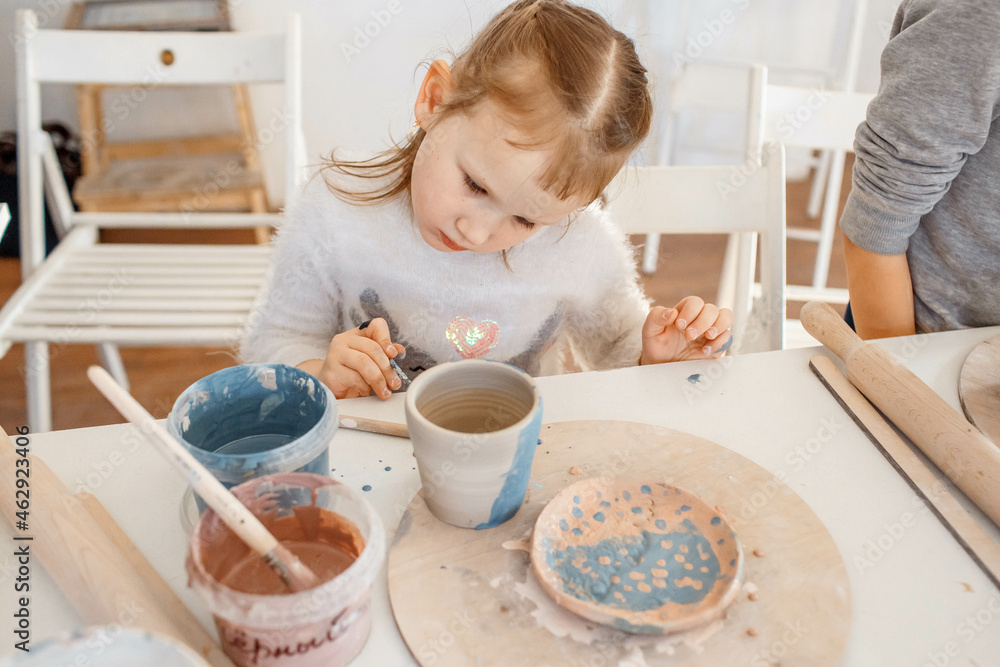 Child working on pottery wheel. Kids arts and crafts class in workshop. Little girl creating cup and bowl of clay. Creative activity in school. Child working on pottery wheel. Kids arts and crafts class in workshop. Little girl creating cup and bowl of clay. Creative activity in school.