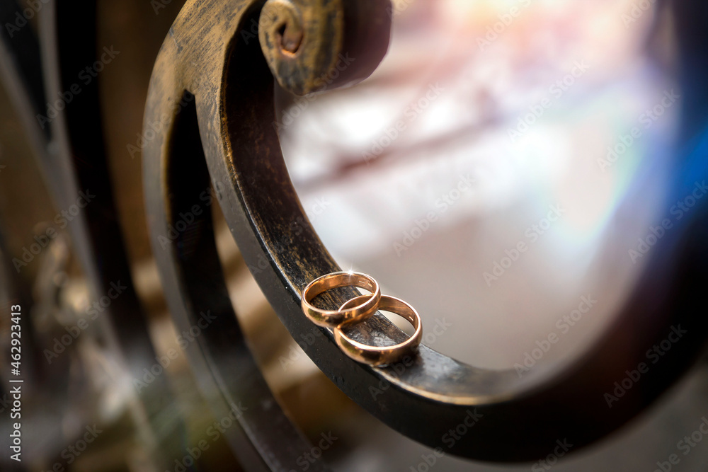 Gold wedding rings on a cast lattice with a blurred background.