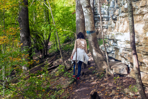 Woman walking along the trail in the autumn mountain forest