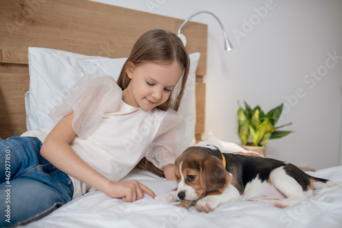 A cute girl playing with her puppy and looking enjoyed