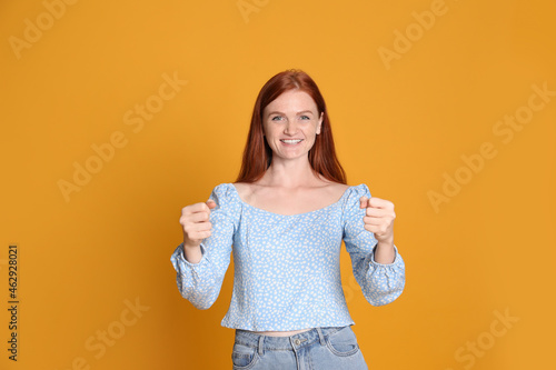 Quadro su tela Happy young woman pretending to drive car on yellow background