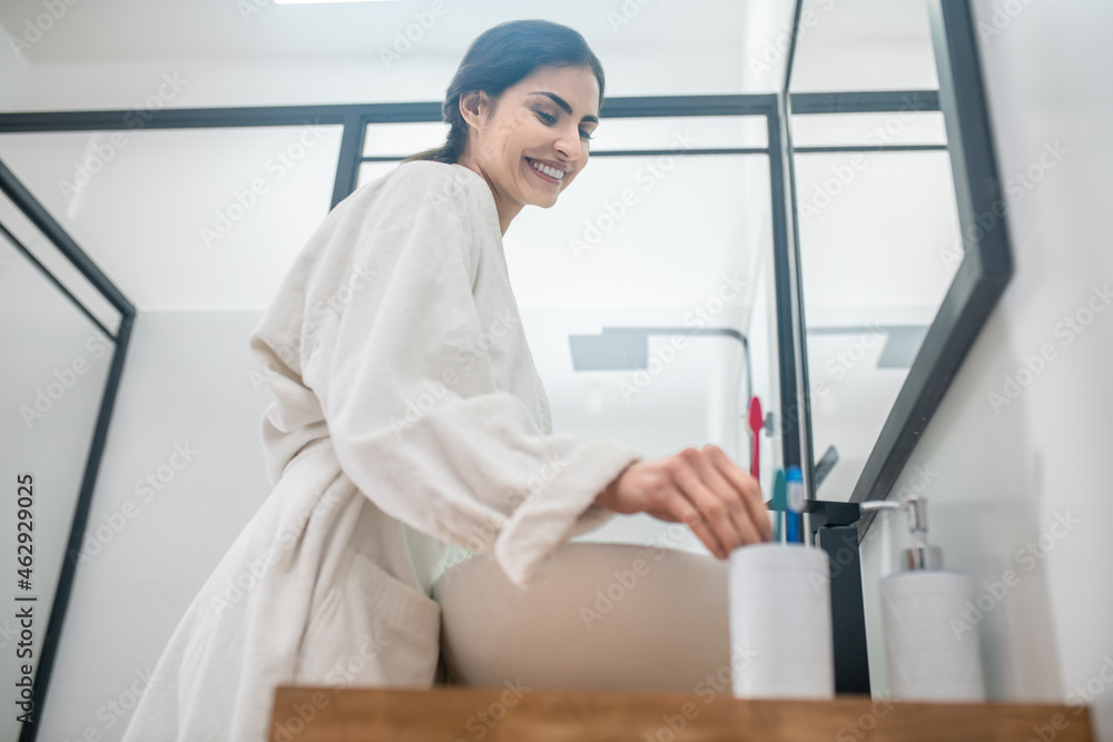 A woman in a white bath robe doing morning procedures in the bathroom A woman in a white bath robe doing morning procedures in the bathroom