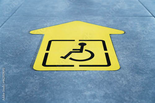 A drawing of a wheelchair on a yellow arrow glued to the tile in the waiting room