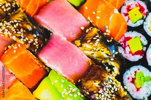 Tasty Colorful assorted Set of different type Sushi. Dinner in Japanese style. Healthy food. Filadelfia and Maki sushi rolls with Avocado, Tuna, Salmon, fish and Prawns. Close up view. Wallpaper.