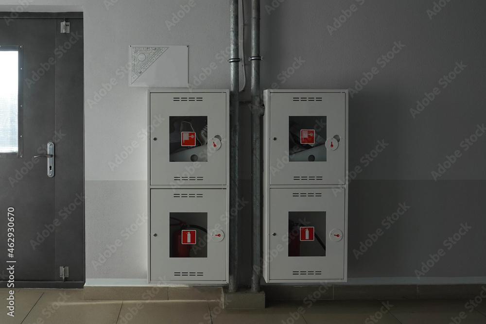Fire extinguisher boxes hanging on a gray wall near the door Fire extinguisher boxes hanging on a gray wall near the door