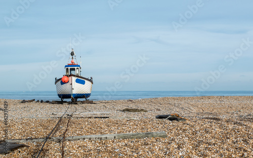 White and blue fishing boat park on rail track at a pebble beach at Dungeness, Kent, England