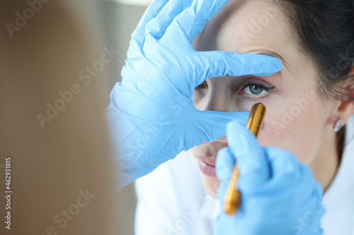 Fotografija Doctor shines light into patient eye to check pupil closeup
