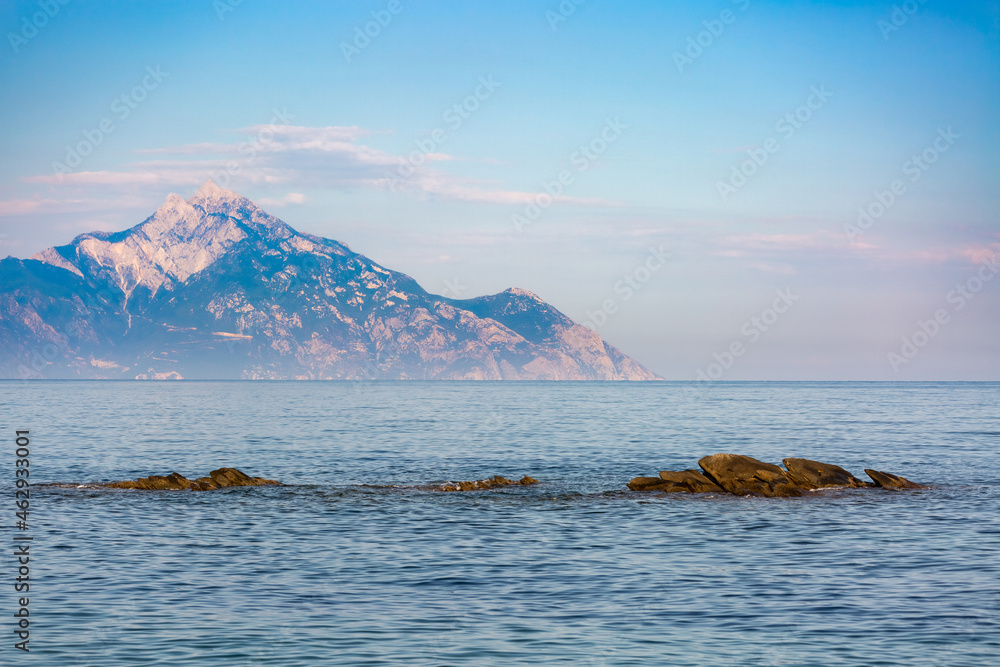 The sacred Mount Athos in Greece seen from Kassandra peninsula in Halkidiki with clear blue sky in background The sacred Mount Athos in Greece seen from Kassandra peninsula in Halkidiki with clear blue sky in background