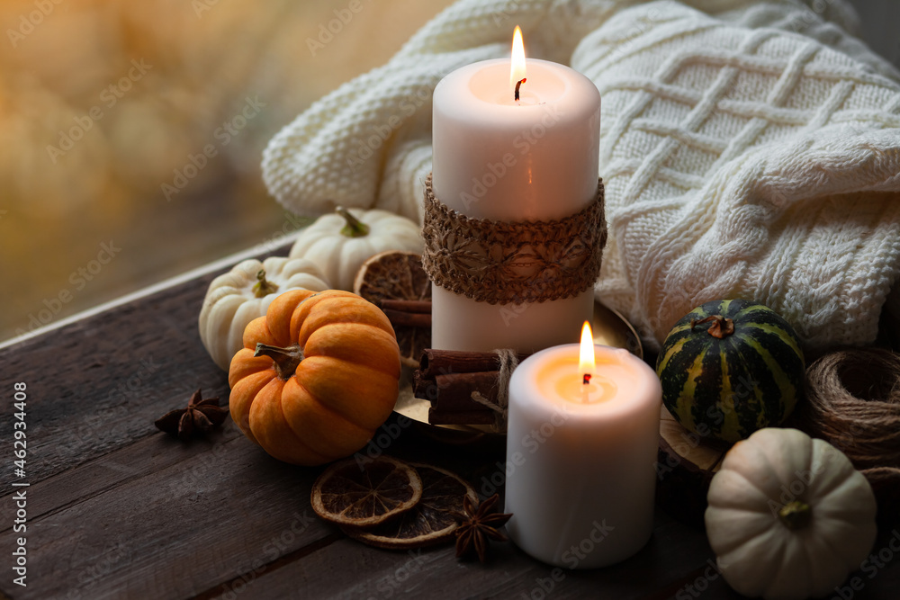 Autumn composition with candles, mini munchkin pumpkins, warm wool knitted plaid on the wooden wind sill. Dark colors, low key. Cozy home atmosphere, Thanksgiving decor, fall colors. Close up Autumn composition with candles, mini munchkin pumpkins, warm wool knitted plaid on the wooden wind sill. Dark colors, low key. Cozy home atmosphere, Thanksgiving decor, fall colors. Close up