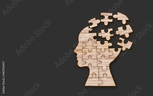 Mental health symbol. Human head silhouette with a puzzle cut out from wooden background