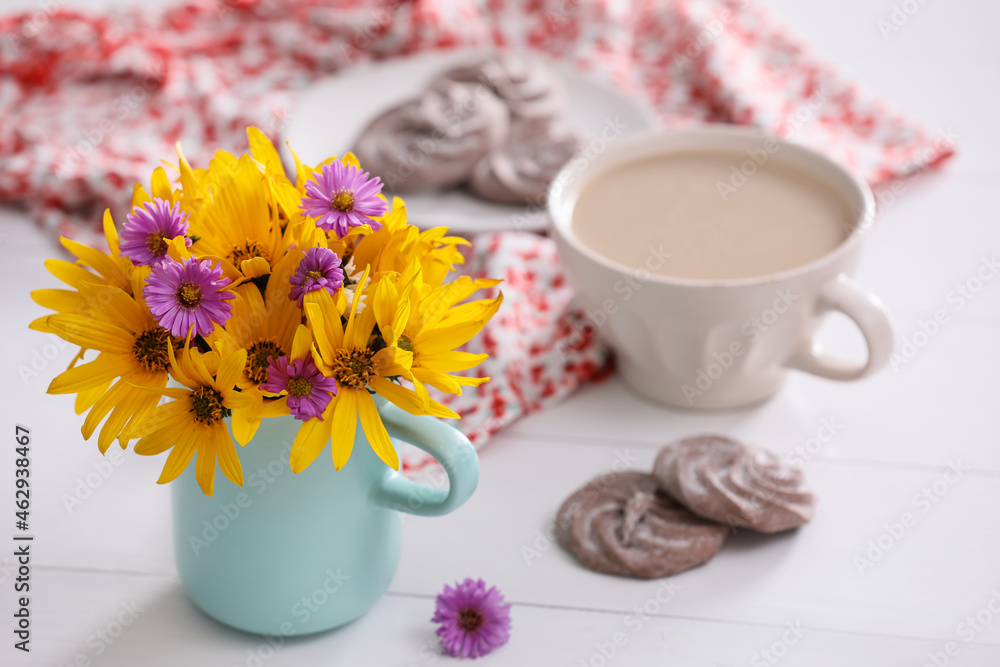 Beautiful bright flowers, cup of coffee, cookies and fabric on white table. Space for text