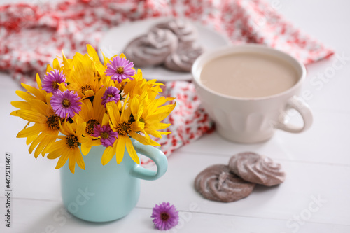 Beautiful bright flowers  cup of coffee  cookies and fabric on white table. Space for text