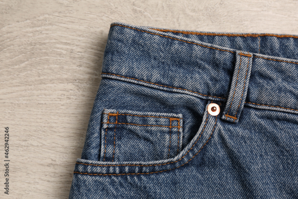 Stylish blue jeans on white wooden background, closeup of inset pocket Stylish blue jeans on white wooden background, closeup of inset pocket