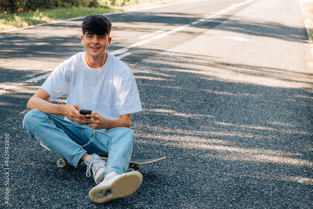 Obraz premium boy with skateboard and headphones on the road