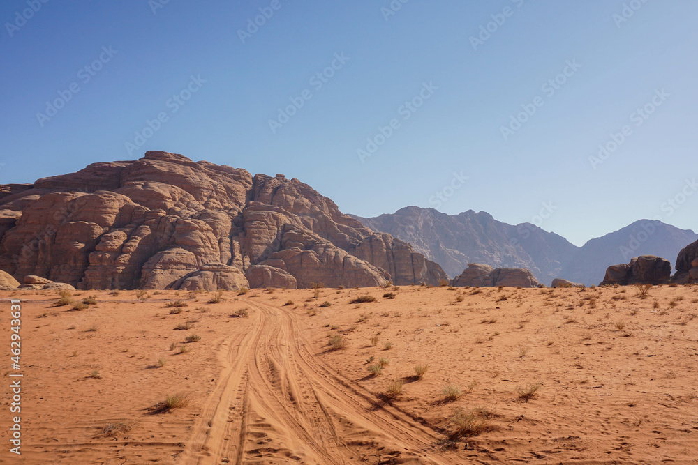 an empty road in the Wadi Rum desert, beautiful red relief mountains are on the horizon, blue cloudless sky, nature of Jordan