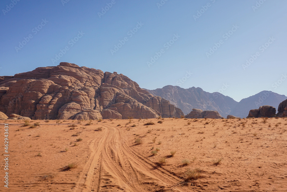 an empty road in the Wadi Rum desert, beautiful red relief mountains are on the horizon, blue cloudless sky, nature of Jordan an empty road in the Wadi Rum desert, beautiful red relief mountains are on the horizon, blue cloudless sky, nature of Jordan