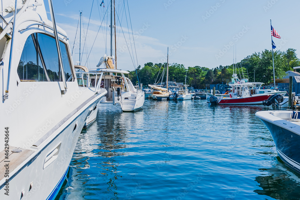 Fototapeta premium Boats and yachts in the port. In the center of the photo, the blue sky is reflected in the blue water