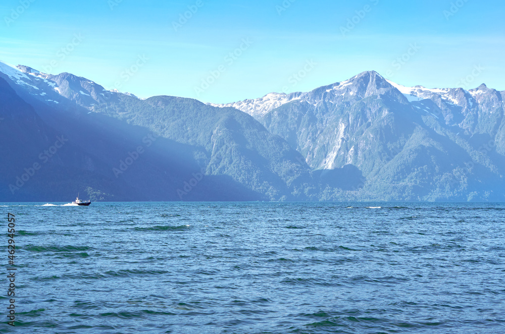 small boat sailing between mountains