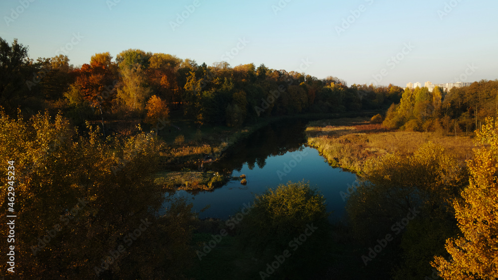 Park area. A winding river with water lilies. Trees with yellow autumn leaves are visible. Aerial photography.