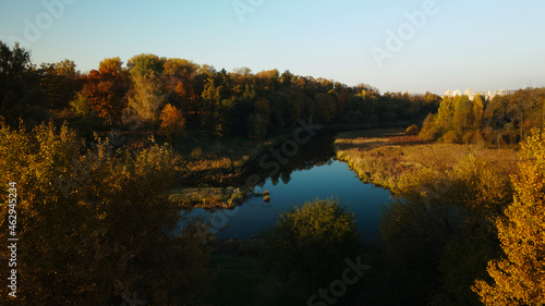 Park area. A winding river with water lilies. Trees with yellow autumn leaves are visible. Aerial photography.