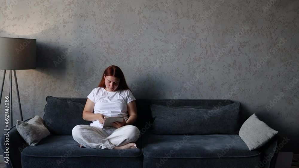 Happy woman relaxing uses a tablet computer at home living room. Happy woman relaxing uses a tablet computer at home living room.