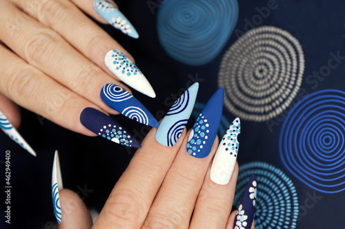 Multicolored blue nail art on a long sharp shape of nails.