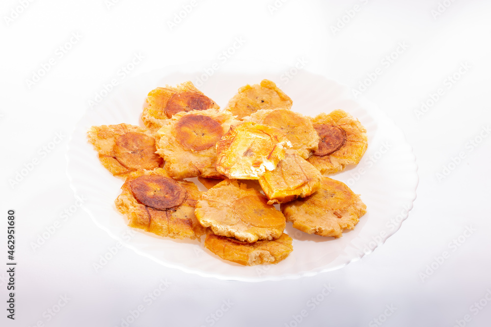 Pile of fried and smashed bananas on white background. Patacones, Tostones, chips, ripe plantain. On a white plate. Pile of fried and smashed bananas on white background. Patacones, Tostones, chips, ripe plantain. On a white plate.