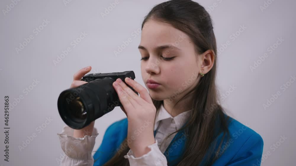 Close-up portrait of beautiful teenage Caucasian girl taking photos with camera standing at white background. Talented creative skilled brunette teenager choosing photographer profession Close-up portrait of beautiful teenage Caucasian girl taking photos with camera standing at white background. Talented creative skilled brunette teenager choosing photographer profession