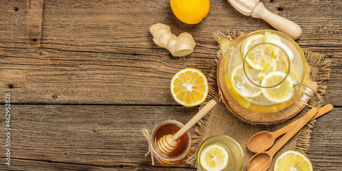 Hot ginger tea with lemon and honey in a glass cup on a wooden boards background